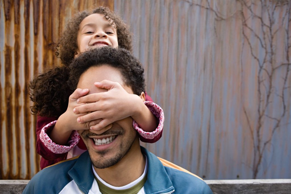 Daughter covering fathers eyes