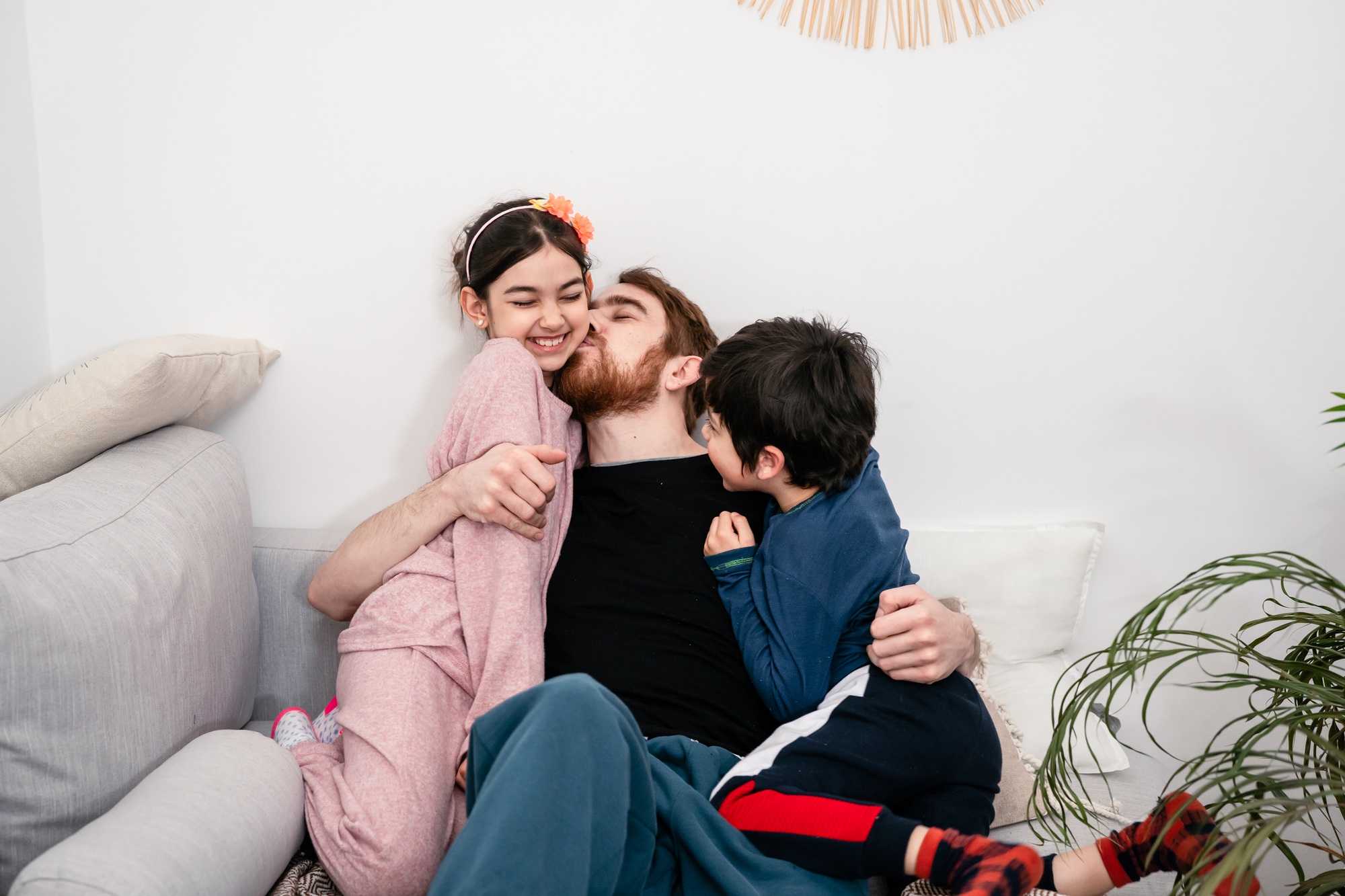 Father and two kids embracing on sofa at home