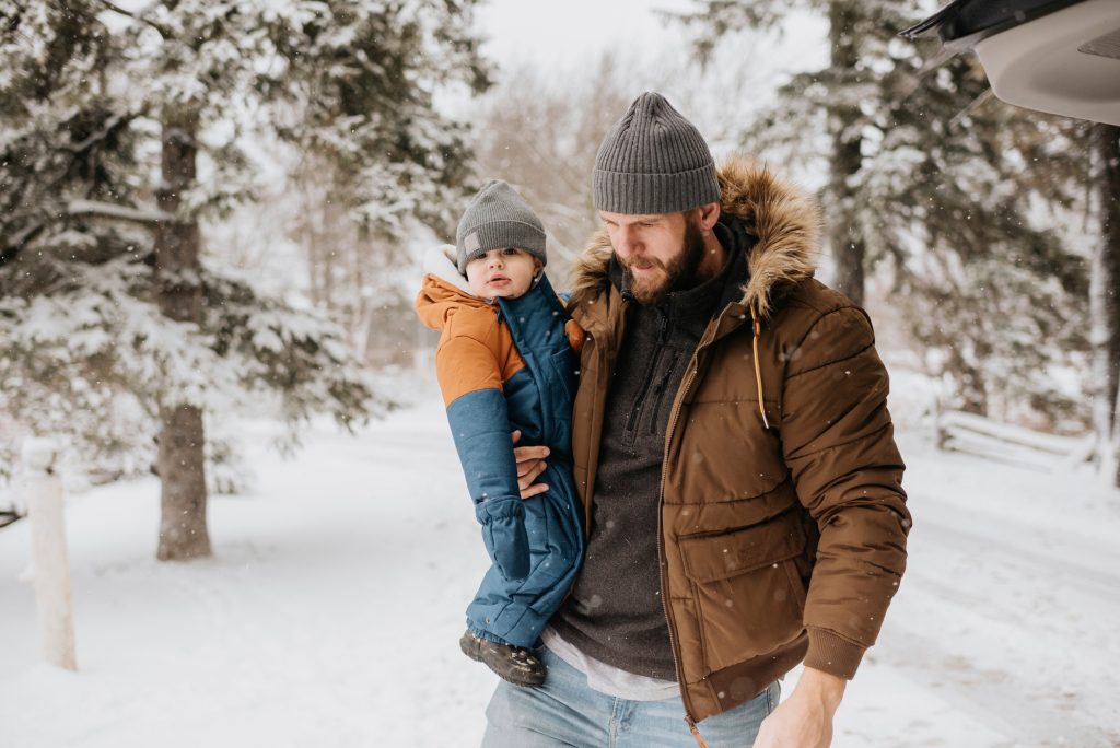 Father carrying his young child on a snowy day.