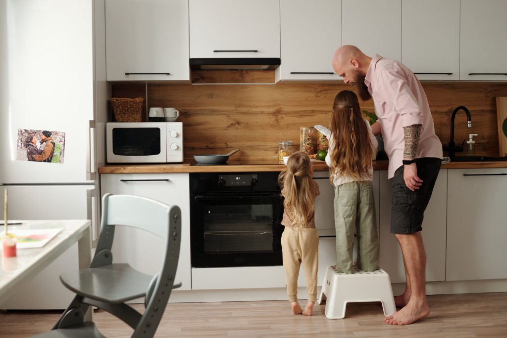 Father cooking with two daughters