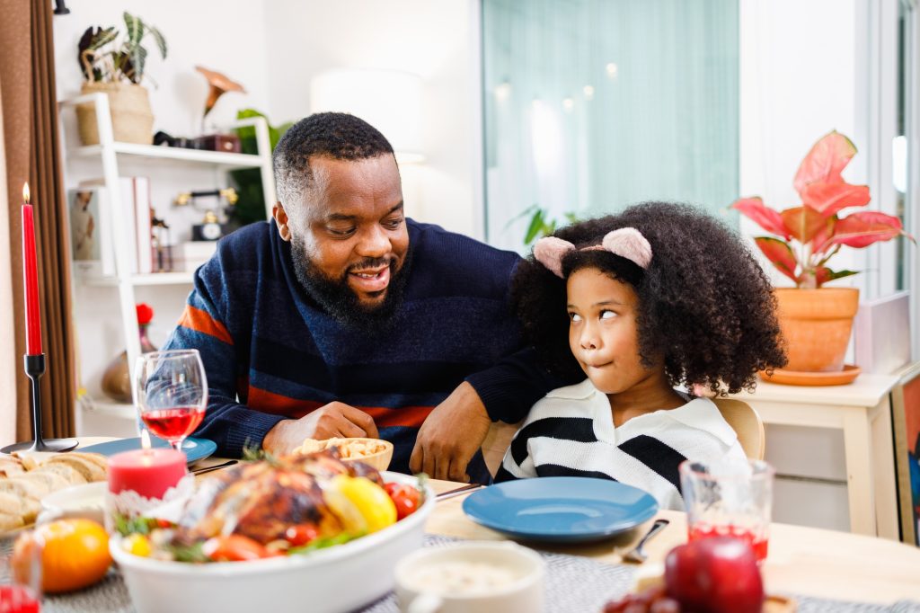 Happy African American family, Father and a little girl with dinner on Thanksgiving day