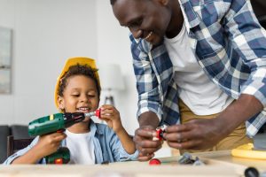 happy african-american father and son playing with toy tools and laughing