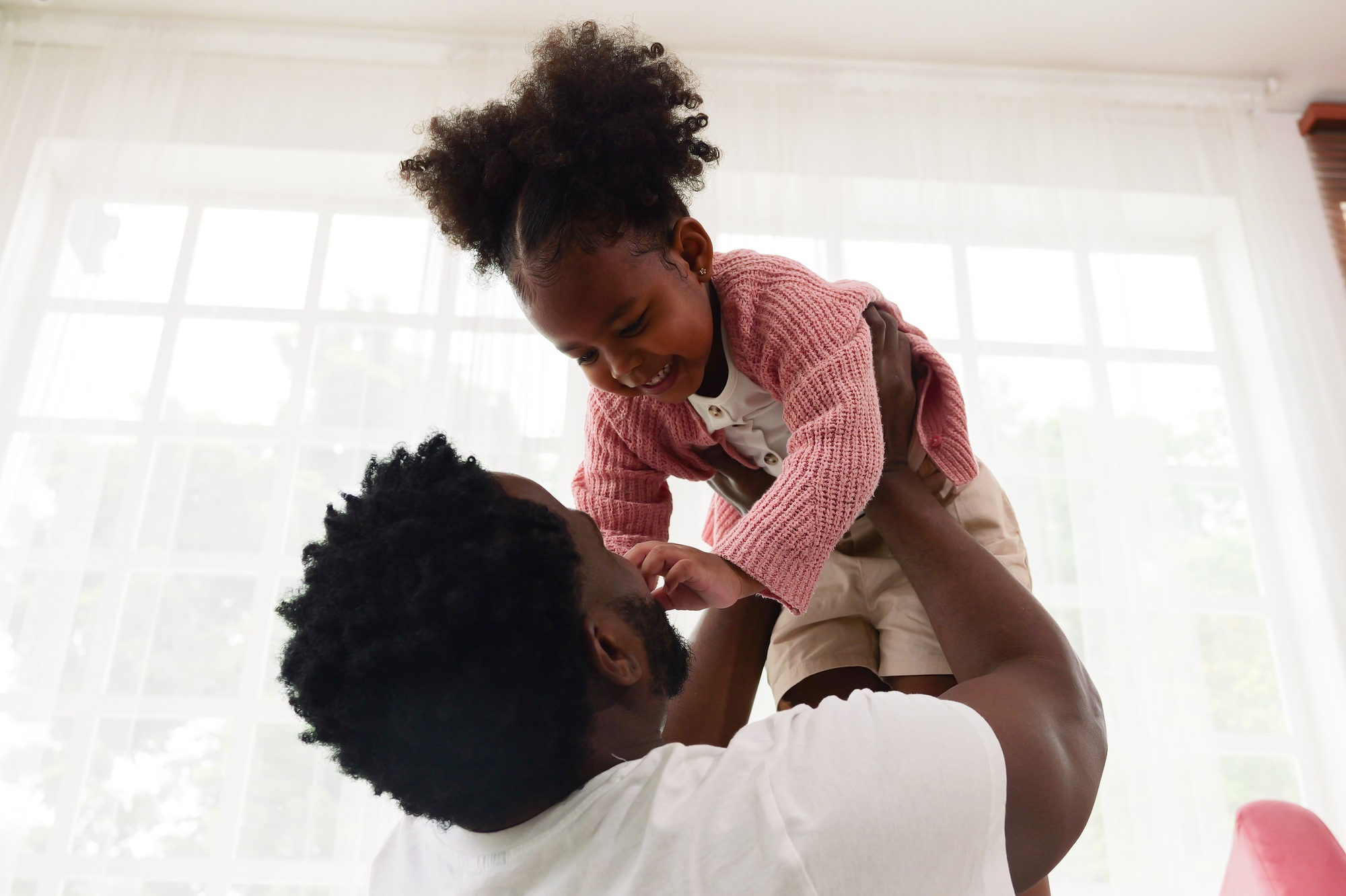 Happy daughter playing with father at home