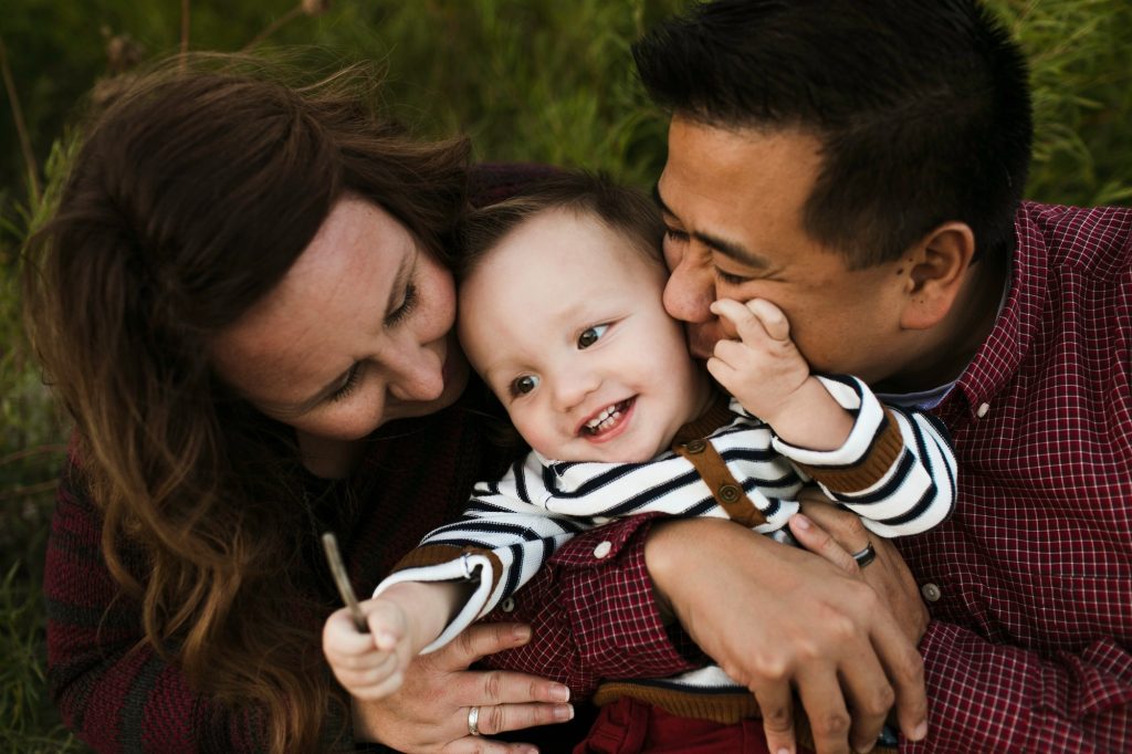 Mother and father hugging smiling baby boy