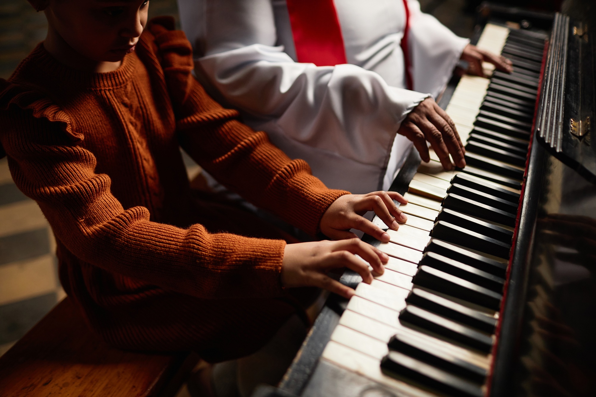 Woman from the church choir teaching girl to play piano